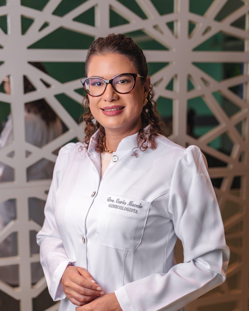 Dra. Carla Macedo de jaleco branco no consultório em Sobral